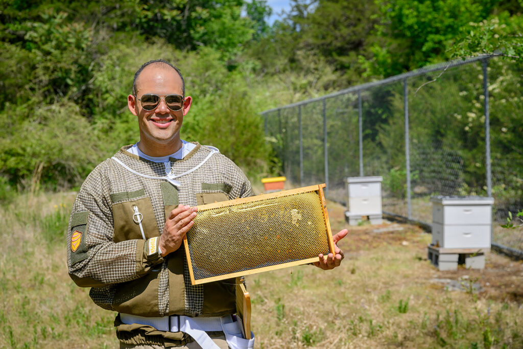 Manuel Giannoni-Guzmán, assistant professor of biology at Middle Tennessee State University in Murfreesboro, Tenn., holds up a beehive frame laden with honey at his outdoor lab located on the MTSU Small Farm facility in Lascassas, Tenn. The professor was awarded a $200,000 U.S. Department of Agriculture grant to study the circadian rhythm of honeybees. (MTSU photo by J. Intintoli)