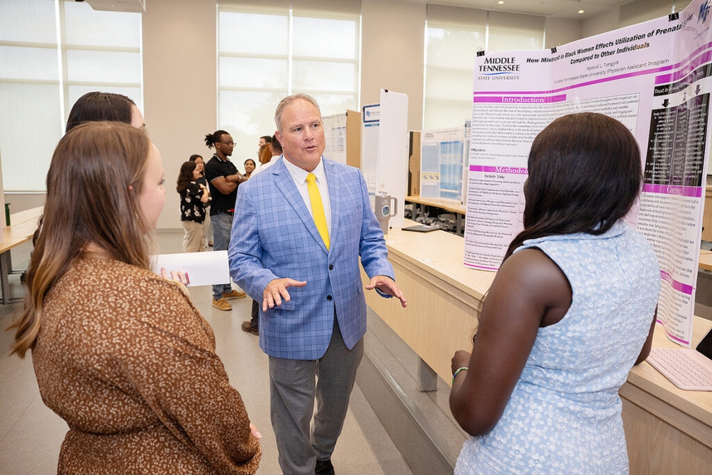 Peter Grandjean, center, dean of the College of Behavioral and Health Sciences at Middle Tennessee State University in Murfreesboro, Tenn., talks with Nyatuil Tongyik, right, a Physician Assistant Studies student who is now in her final semester, during her first-year student poster presentation on display at the 2025 Capstone and Poster Symposium. This year’s event, when Tongyik will give her final research presentation, is 11:30 a.m. to 4:30 p.m. Friday, July 31, in the Academic Classroom Building, 1751 MTSU Blvd. (MTSU file photo by James Cessna)