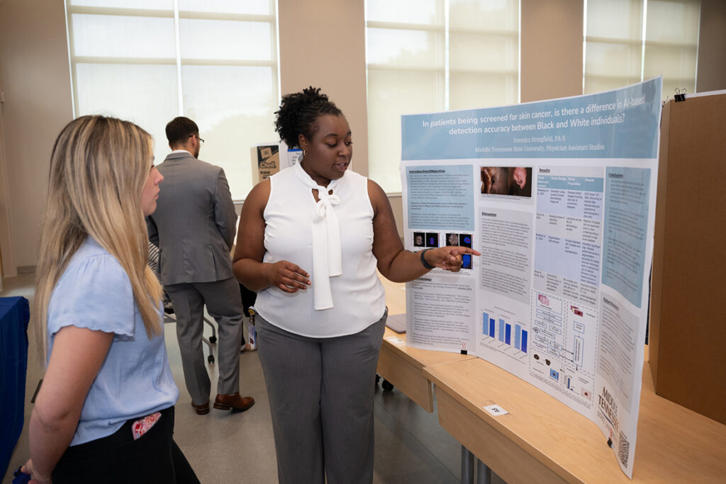 Veronica Stringfield, right, a Physician Assistant Studies student at Middle Tennessee State University in Murfreesboro, Tenn., talks about the research poster she presented as a first-year student at the 2025 Capstone and Poster Symposium. This year’s event, when Stringfield will give her final research presentation, is 11:30 a.m. to 4:30 p.m. Friday, July 31, in the Academic Classroom Building, 1751 MTSU Blvd. (MTSU file photo by James Cessna)