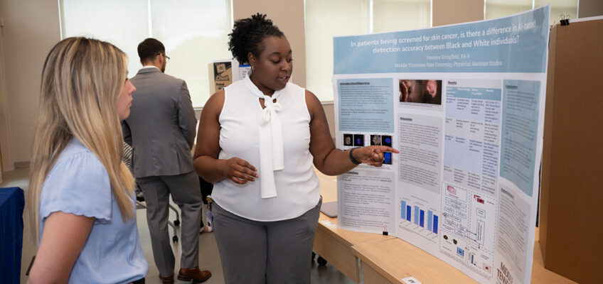Veronica Stringfield, right, a Physician Assistant Studies student at Middle Tennessee State University in Murfreesboro, Tenn., talks about the research poster she presented as a first-year student at the 2025 Capstone and Poster Symposium. This year’s event, when Stringfield will give her final research presentation, is 11:30 a.m. to 4:30 p.m. Friday, July 31, in the Academic Classroom Building, 1751 MTSU Blvd. (MTSU file photo by James Cessna)