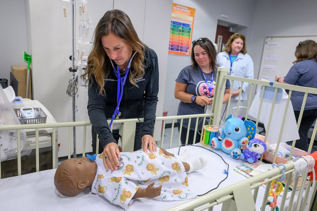 Lisa Hollifield, a school nurse with Rutherford County Schools, checks a high-fidelity pediatric mannequin for any signs of asthma distress while fellow nurse Keisha Newport looks on during School Nurse Skills Day hosted in June at Middle Tennessee State University School of Nursing in Murfreesboro, Tenn. (MTSU photo by J. Intintoli)
