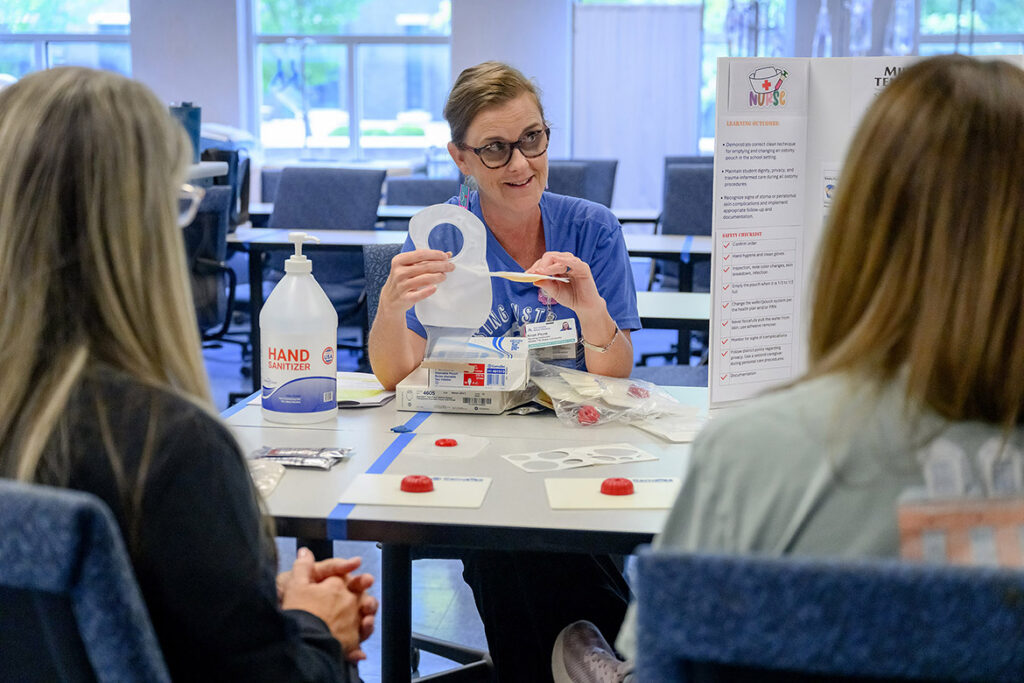 Kristi Plunk, center, a clinical associate professor of nursing at Middle Tennessee State University School of Nursing in Murfreesboro, Tenn., shares tips with school nurses on proper adhesion of a skin barrier for an ostomy bag during the School Nurse Skills Day hosted in June at MTSU’s School of Nursing. (MTSU photo by J. Intintoli)