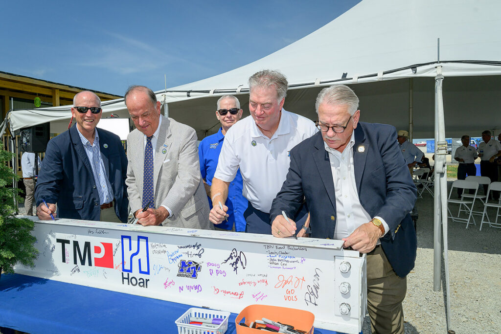 Pictured front row, from left, Middle Tennessee State University Board of Trustees members Jimmy Granbery, Chairman Stephen Smith and John Floyd and Shelbyville Mayor Randy Carroll sign the ceremonial beam at the topping-out ceremony held Tuesday, July 21, for the $62 million flight training center for MTSU’s Aerospace Department under construction at the Shelbyville, Tenn., Municipal Airport in Bedford County. In the background, awaiting his opportunity to sign, is MTSU Trustee Tom Boyd. (MTSU photo by J. Intintoli)