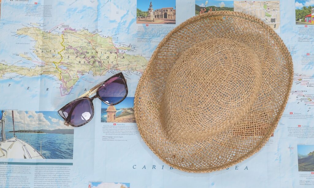 Travel map of islands, straw hat, and sunglasses to depict tourism