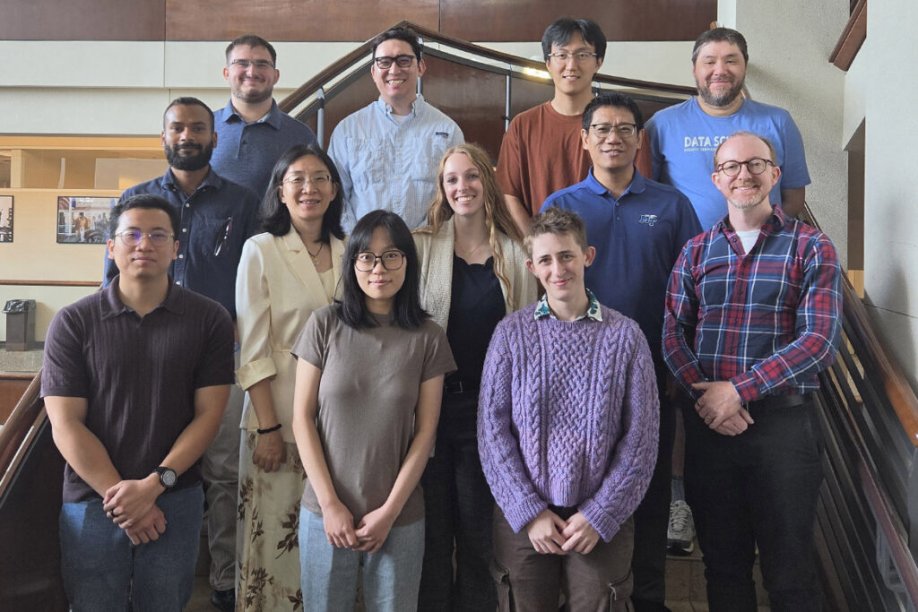 Three rows of MTSU students and faculty pose on the staircase of Walker Library, looking at the camera. 