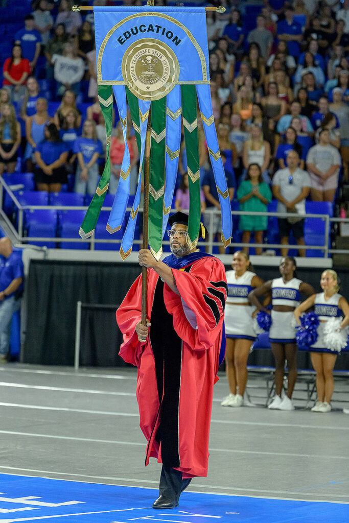 Peter Eley, associate dean for Curriculum, Assessment and Academic Policy in the College of Education at Middle Tennessee State University in Murfreesboro, Tenn., holds the college banner during the processional at the 25th annual Convocation held Saturday, Aug. 22, inside Murphy Center on campus. (MTSU photo by Andy Heidt)