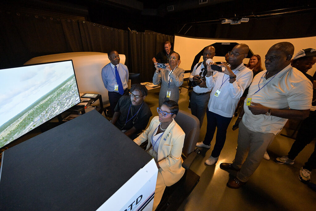 Led by Middle Tennessee State University President Sidney A. McPhee, top left, members of a delegation from the Commonwealth of the Bahamas tour Middle Tennessee State University’s Aerospace facilities at the Murfreesboro, Tenn., municipal airport on Wednesday, Aug. 12, 2026. JoBeth Coleby-Davis, minister of energy, utilities and aviation for the Bahamas, seated right, tries out an aerospace simulator. She and McPhee signed an aerospace education agreement between the university and the commonwealth allowing Bahamian students to take aviation courses through MTSU. (MTSU photo by Andy Heidt)