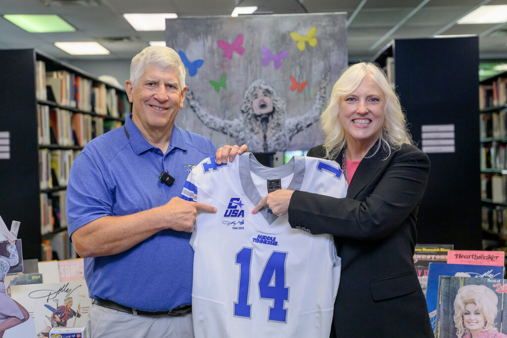 Standing inside Middle Tennessee State University’s Center for Popular Music, Athletics Director Chris Massaro, left, and Beverly Keel, dean of the MTSU Scott Borchetta College of Media and Entertainment, point to the jersey patch honoring late country music legend Dolly Parton that will be placed on the uniforms of the Blue Raider football team for its season opener Sept. 5 at Floyd Stadium in Murfreesboro, Tenn. (MTSU photo by J. Intintoli)
