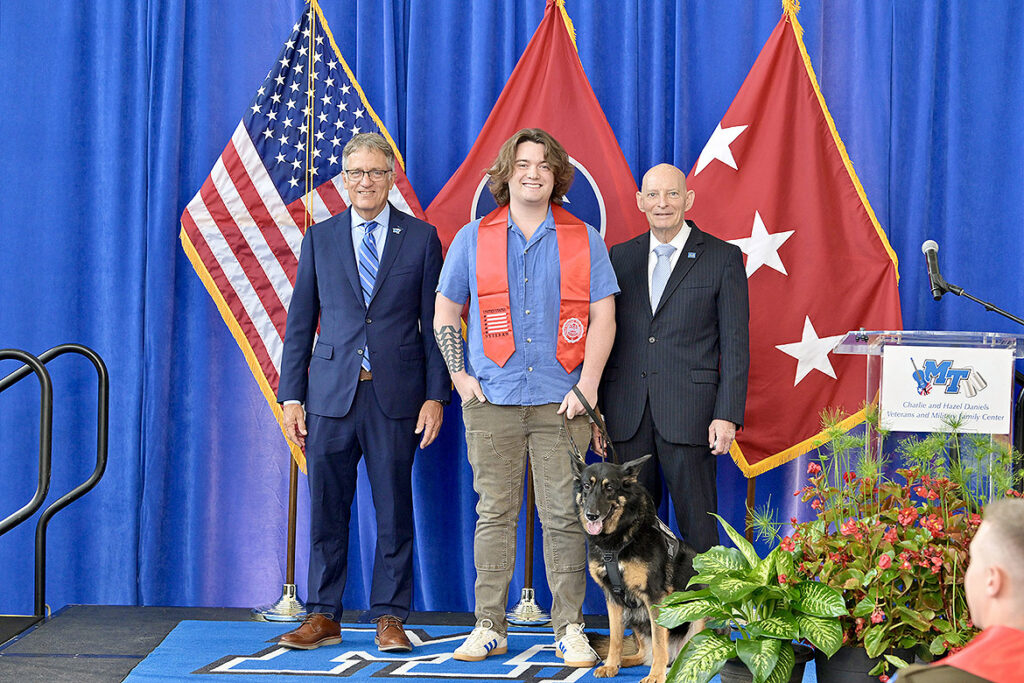 Middle Tennessee State University Provost Mark Byrnes, left, and retired Lt. Gen. Keith M. Huber, senior adviser for veterans and leadership initiatives at MTSU, right, stand with U.S. Army veteran John Farris and his guide-dog-in-training, Ellie, on stage following the Charlie and Hazel Daniels Veterans and Military Family Center’s 34th Graduating Veterans Stole Ceremony held Thursday, Aug. 6, at Miller Education Center on campus in Murfreesboro, Tenn. Farris will graduate Saturday, Aug. 8, with a bachelor of science degree from the Department of Aerospace and credits the Daniels Center with helping him succeed. (MTSU photo by Andy Heidt)