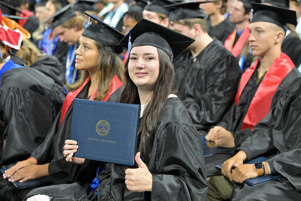 A proud Middle Tennessee State University graduate gives a thumbs up while holding her diploma cover during the summer commencement ceremony held Saturday, Aug. 8, 2026, inside Murphy Center on campus in Murfreesboro, Tenn. (MTSU photo by James Cessna)