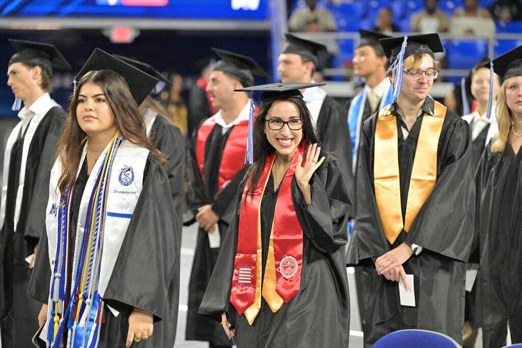 A proud Middle Tennessee State University graduating student veteran, wearing the signature red stole, waves to a supporter during the summer commencement ceremony held Saturday, Aug. 8, 2026, inside Murphy Center on campus in Murfreesboro, Tenn. (MTSU photo by James Cessna)