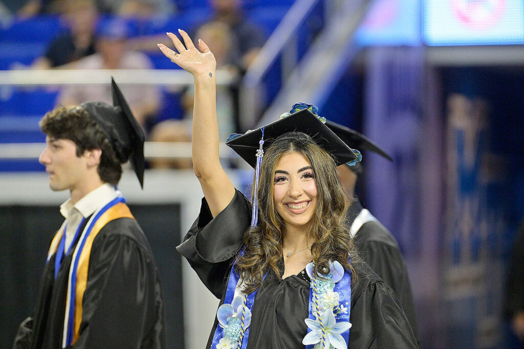 A Middle Tennessee State University Class of 2026 graduate gives a celebratory wave to the crowd gathered inside Murphy Center on campus in Murfreesboro, Tenn., during the summer commencement ceremony held Saturday, Aug. 8, 2026. (MTSU photo by Andy Heidt)