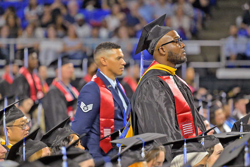 Wearing red stoles to signify their military service, Middle Tennessee State University student veterans stand to be recognized during the summer commencement ceremony held on Saturday, Aug. 8, 2026, inside Murphy Center on campus in Murfreesboro, Tenn. (MTSU photo by Andy Heidt)