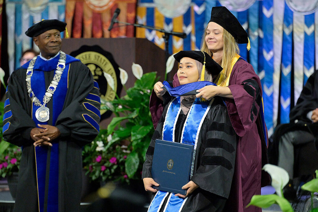 Liz Barnes, associate professor of biology at Middle Tennessee State University in Murfreesboro, Tenn., hoods doctoral recipient Rahmi Qurota Aini during the summer commencement ceremony on Saturday, Aug. 8, 2026, 2026, inside Murphy Center on campus. (MTSU photo by Andy Heidt)