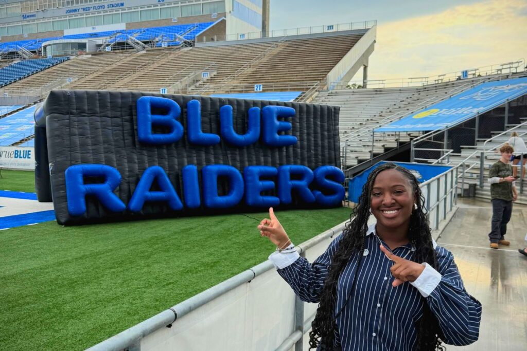 Middle Tennessee State University Student Government Association President Kennedy Garrett, of Chattanooga, Tenn., points to the “Blue Raiders” emblazoned on the football team’s inflatable tunnel in this undated photo just off the field at Johnny "Red" Floyd Stadium on the Murfreesboro, Tenn., campus. (Photo submitted)