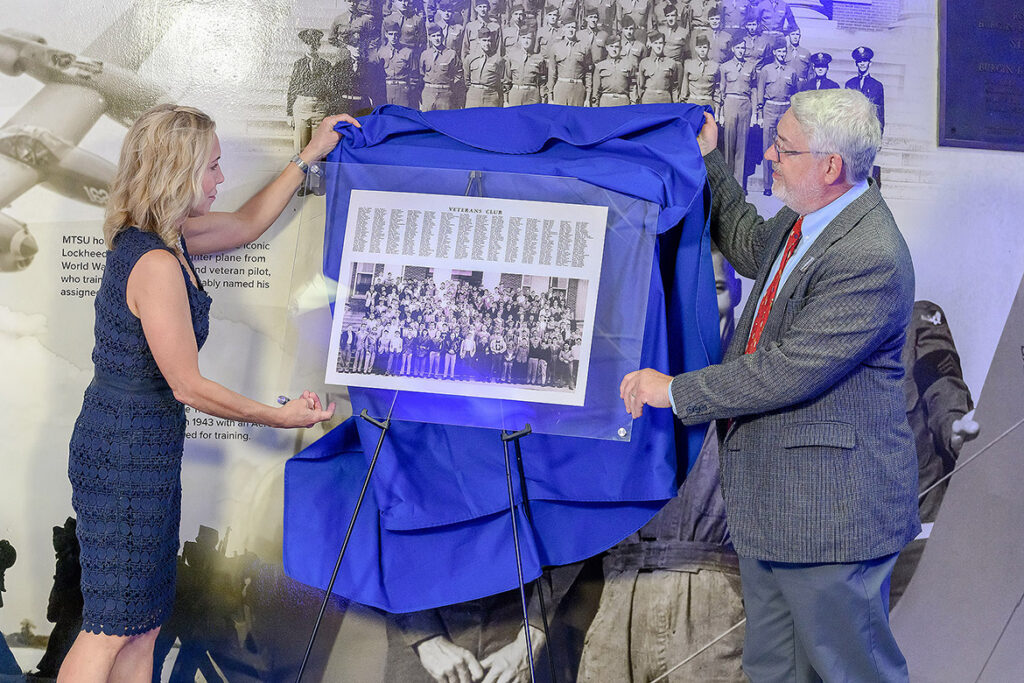 An enlarged Midlander yearbook photo of Veterans Club members at Middle Tennessee State University in Murfreesboro, Tenn., is presented by Hilary Miller, director of the Charlie and Hazel Daniels Veterans and Military Family Center, at left, and Louis Kyriakoudes, director of the Albert Gore Research Center, during the unveiling ceremony of the World War II Memorial located in Alumni Memorial Gym on Wednesday, Sept. 2, 2026. A whole host of administrators, alumni, military veterans, staff and students were on hand for the event. (MTSU photo by J. Intintoli)