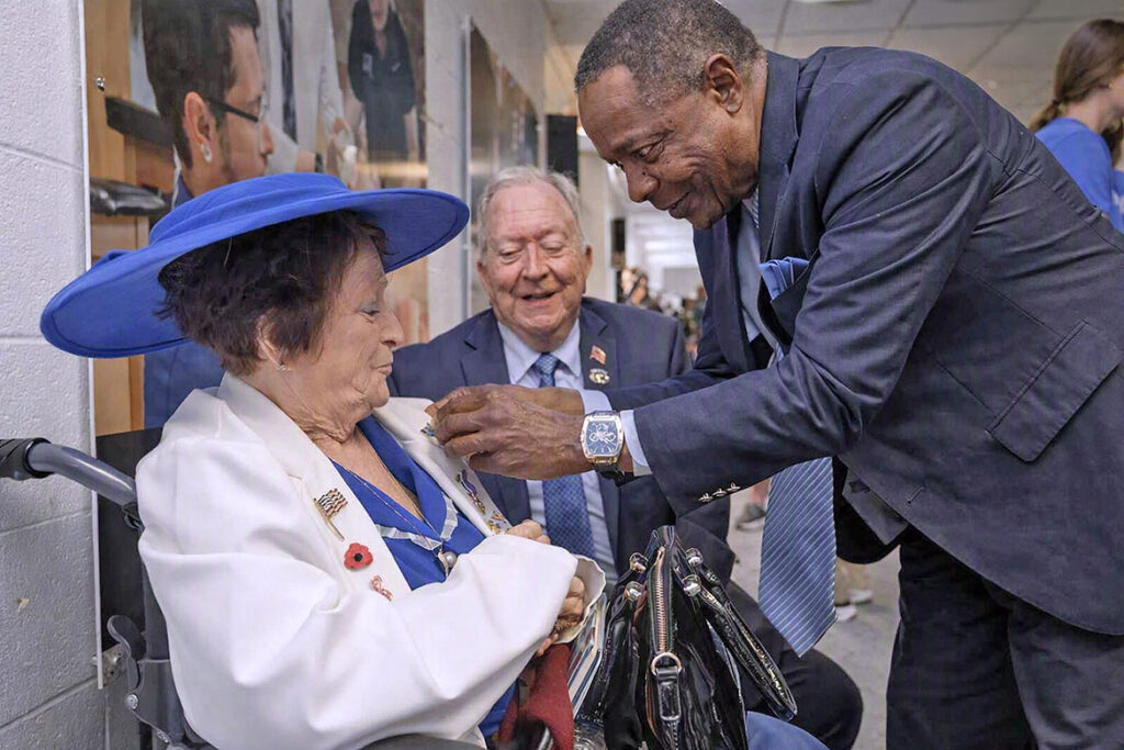 Middle Tennessee State University President Sidney A. McPhee, right, pins a commemorative MTSU brooch to the label of Jane McCalmont, wife of retired Lt. Col. Robert “Bob” McCalmont, in back, during the unveiling ceremony of the World War II Memorial located in Alumni Memorial Gym on Wednesday, Sept. 2, 2026. A whole host of administrators, alumni, military veterans, staff and students were on hand for the event. (MTSU photo by J. Intintoli)
