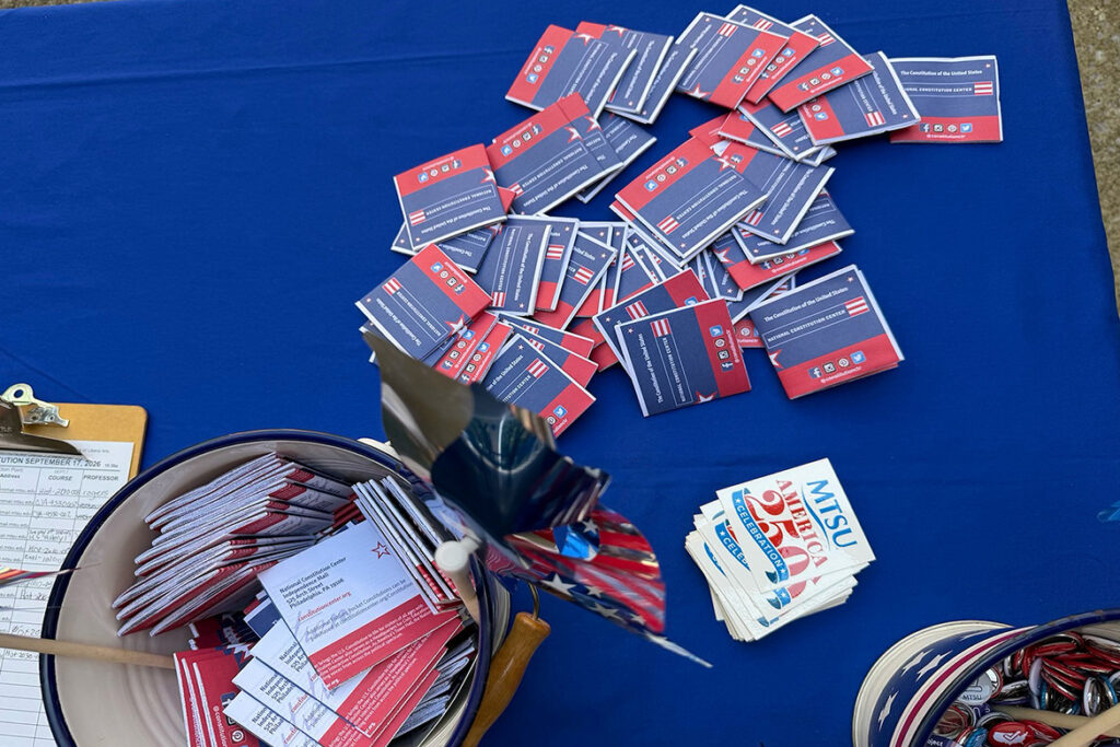 Small multicolored pamphlets spread across top of table with others inside a small bucket.