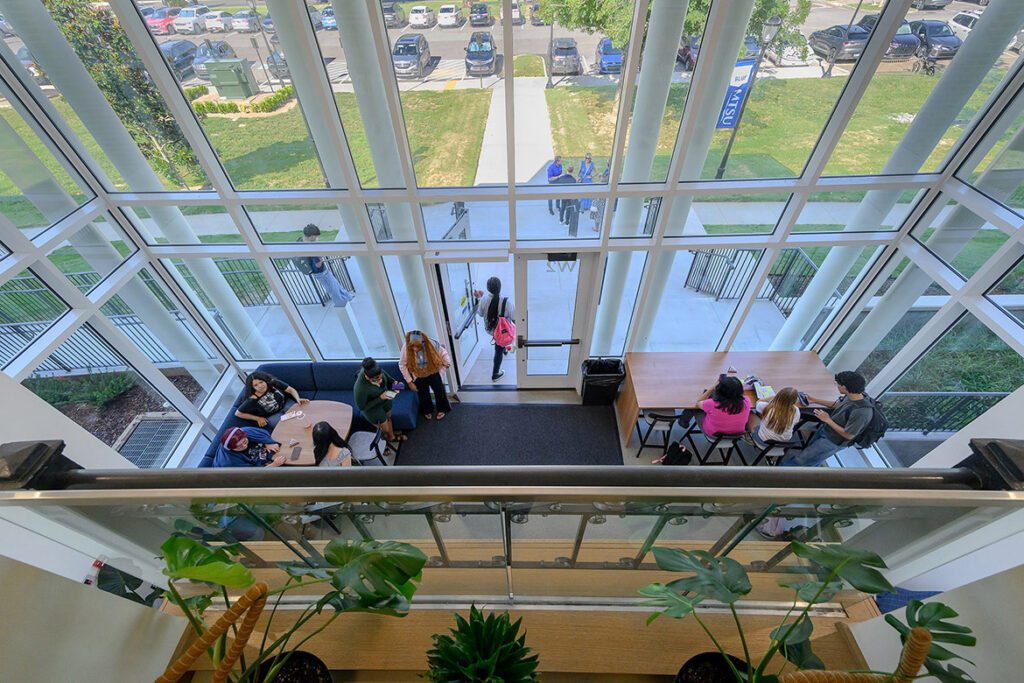 The view from a small balcony looks down into a lobby of people.