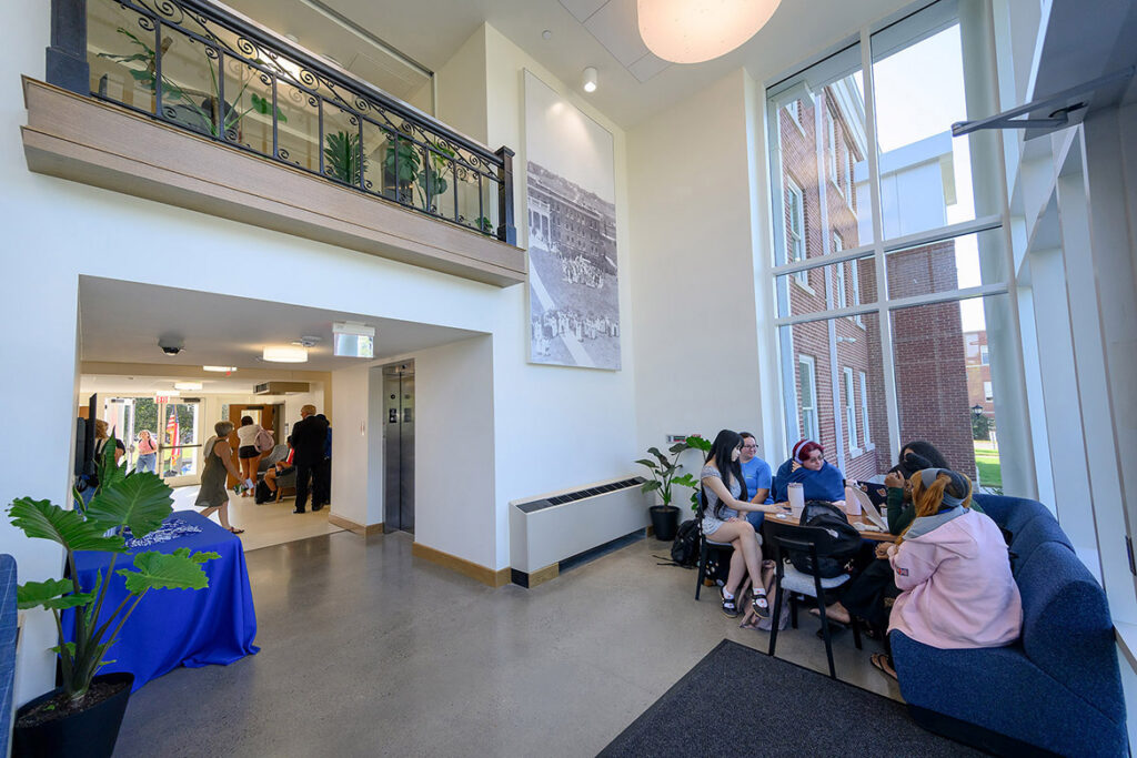 A group of students sit on a blue couch, talking. 