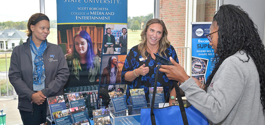 Two MTSU female employees speaking with attendee to True Blue Tour stop.