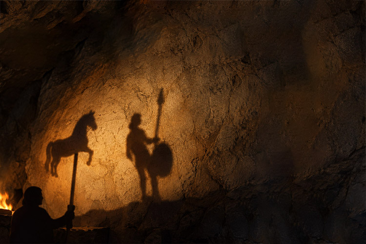The ancient philosopher Plato imagined people confined inside a cave, able to see only shadows projected onto a wall. Those shadows became their reality because they had never seen anything else. Applied Philosophy Lyceum speaker Dr. John Kaag sees a modern version of that cave in the algorithms that increasingly shape what people encounter online in an era of “industrial-scale shadow play.” (Adobe Stock photo)