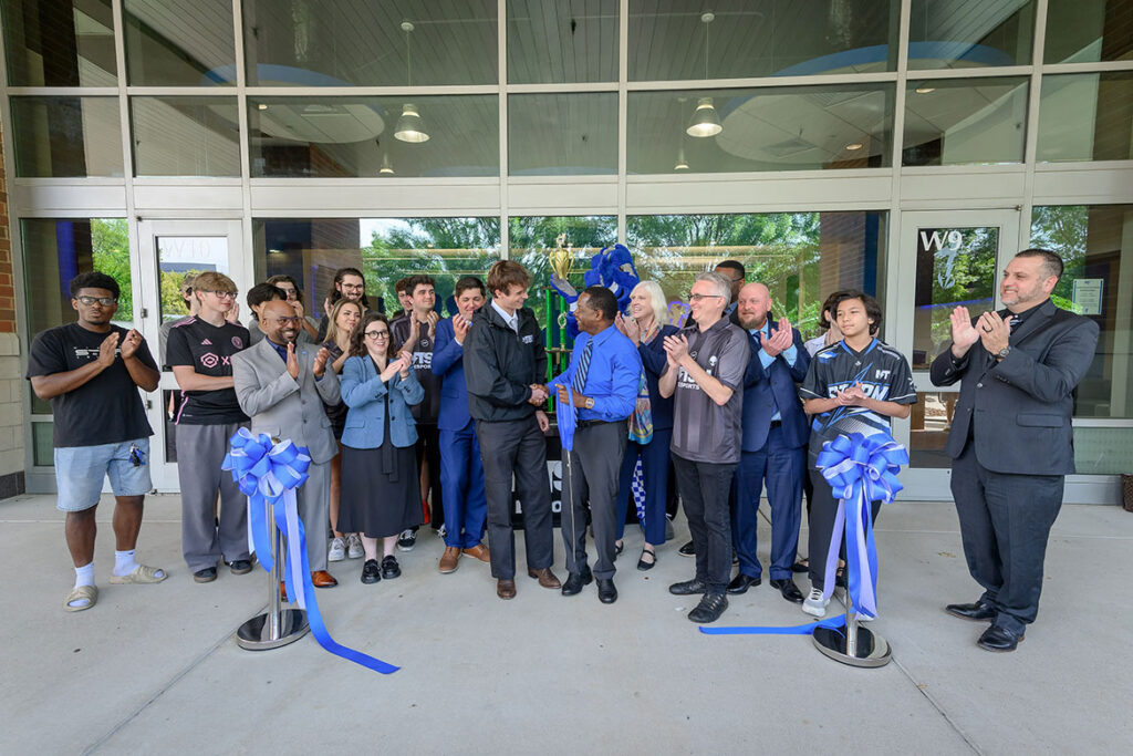 Middle Tennessee State University President Sidney A. McPhee, center, shakes hands with Kyle Greaney, a video and film production student from Memphis, Tenn., and vice president of MTSU Esports, as university administrators, faculty and XP League of Franklin applaud the Tuesday, Sept. 22, 2026, ribbon cutting for the newly expanded Esports Level Up Arena located in the Student Union Building on campus in Murfreesboro, Tenn. (MTSU Photo by J. Intintoli)