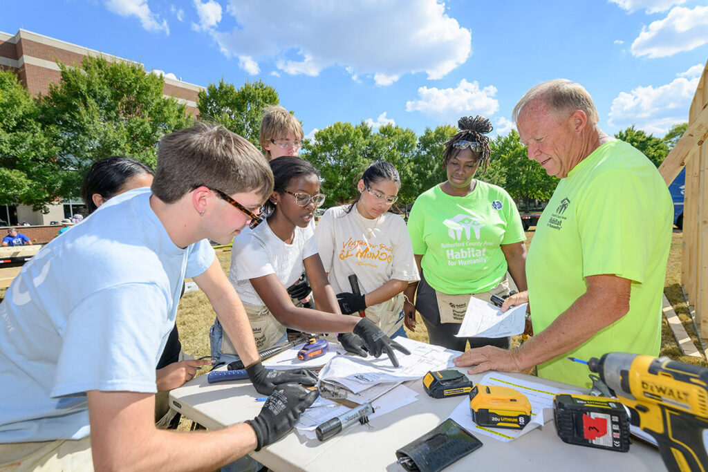 Future homeowner Cle-etta Jefferson, second from right, listens as Habitat for Humanity Construction Director Steve Arnold, right, talks with a group of student volunteers at Middle Tennessee State University’s annual Habitat for Humanity panel build on Thursday, Oct. 1, 2026, the Student Union Commons in Murfreesboro, Tenn. (MTSU Photo by J. Intintoli)
