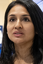 A woman with tan skin, dark hair and brown eyes speaking.