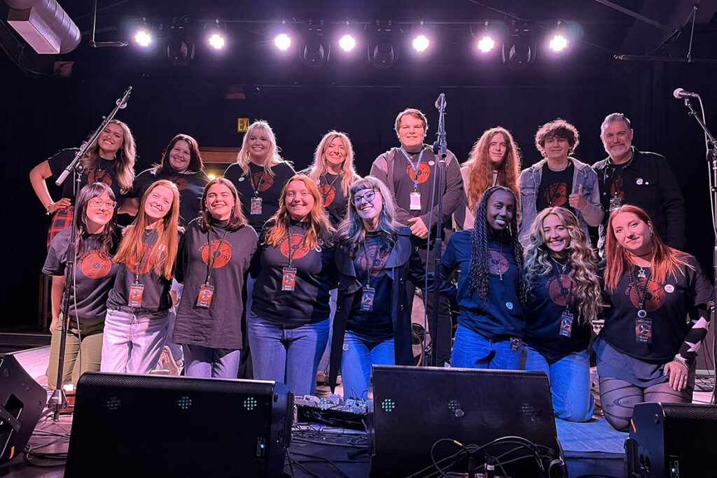 In this file image, Adam Caress, back row at right, assistant professor of recording industry at Middle Tennessee State University in Murfreesboro, Tenn., takes a group photo with students in one of his live concert planning classes. MTSU Department of Recording Industry has been named among Billboard’s top music business schools for the 12th consecutive year. (MTSU file photo)