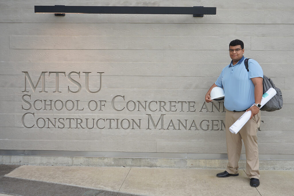 With hard hat and building plans in hand, Middle Tennessee State University construction management major Lucas Daggs stands in front of the School of Concrete and Construction Management. (MTSU photo by Robin E. Lee).