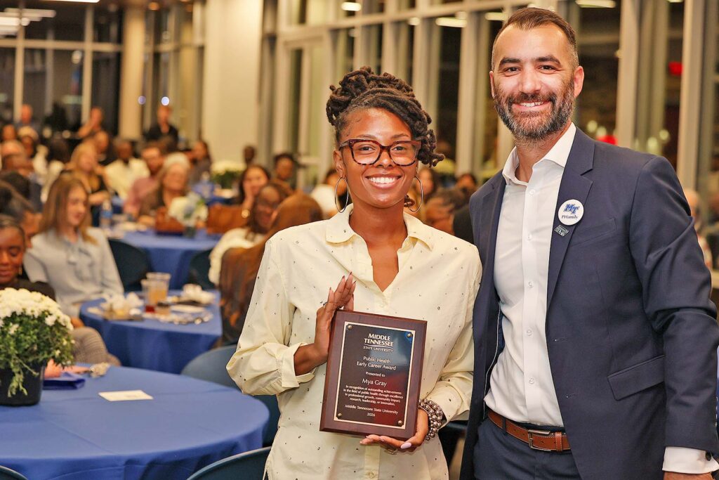 Kahler Stone, right, associate professor of public health in the Department of Health Sciences at Middle Tennessee State University in Murfreesboro, Tenn., presents the Early Career Award to MTSU alumna Mya Gray, STI/HIV Program coordinator for the Metro Nashville Health Department, at the annual Public Health Program PHamily Dinner held in September 2026. (Submitted photo)