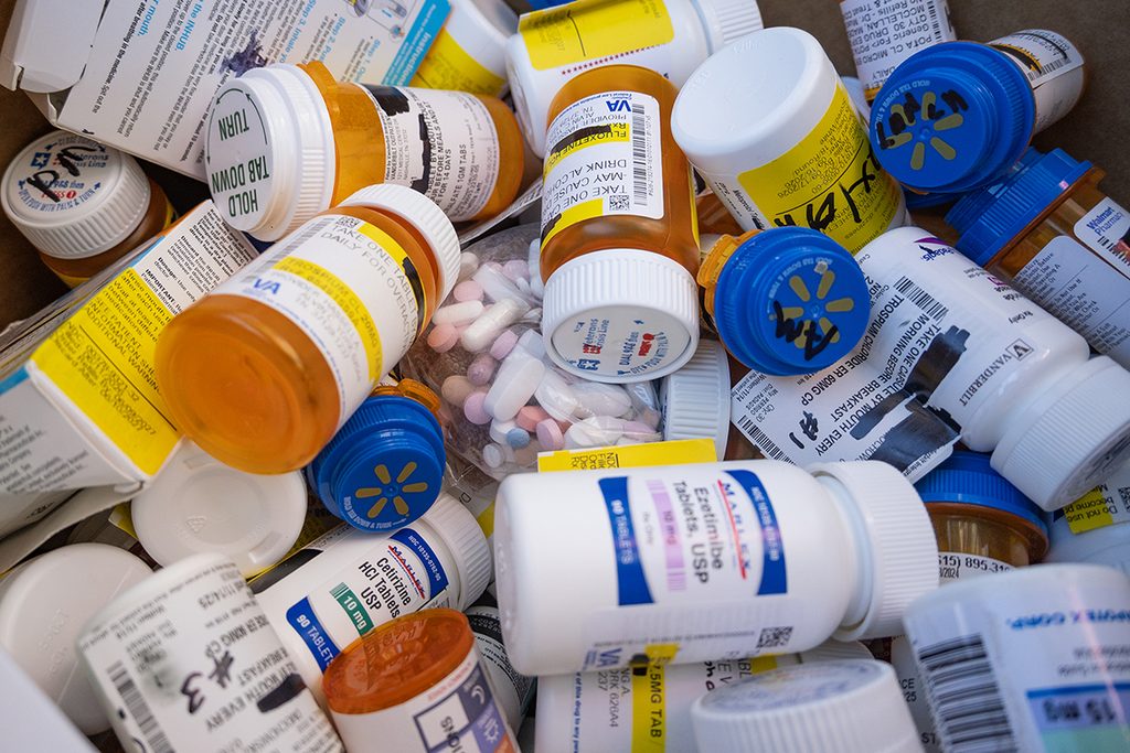 A close up look at prescription bottles, boxes and baggies of pills.